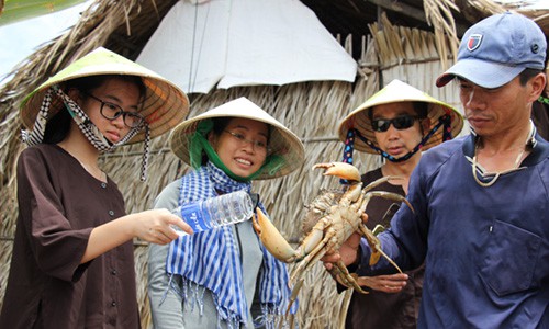 Ngọc Hiện (choàng khăn) giới thiệu cua biển tự nhiên với du khách. Ảnh: Hoàng Nam